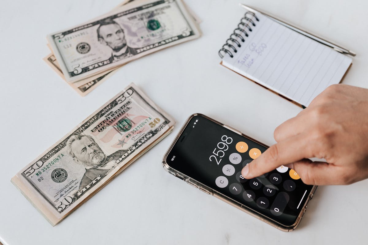 Calculatrice et carnet à côté de billets de banque sur un bureau