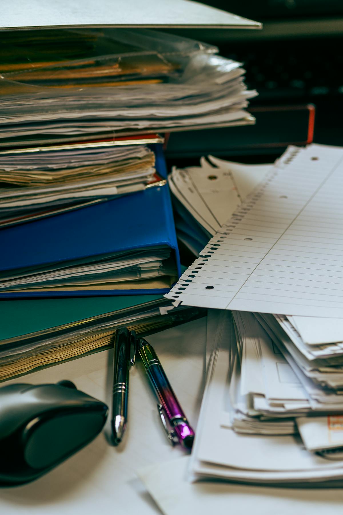 Bureau organisé avec piles de papiers, dossiers et stylos