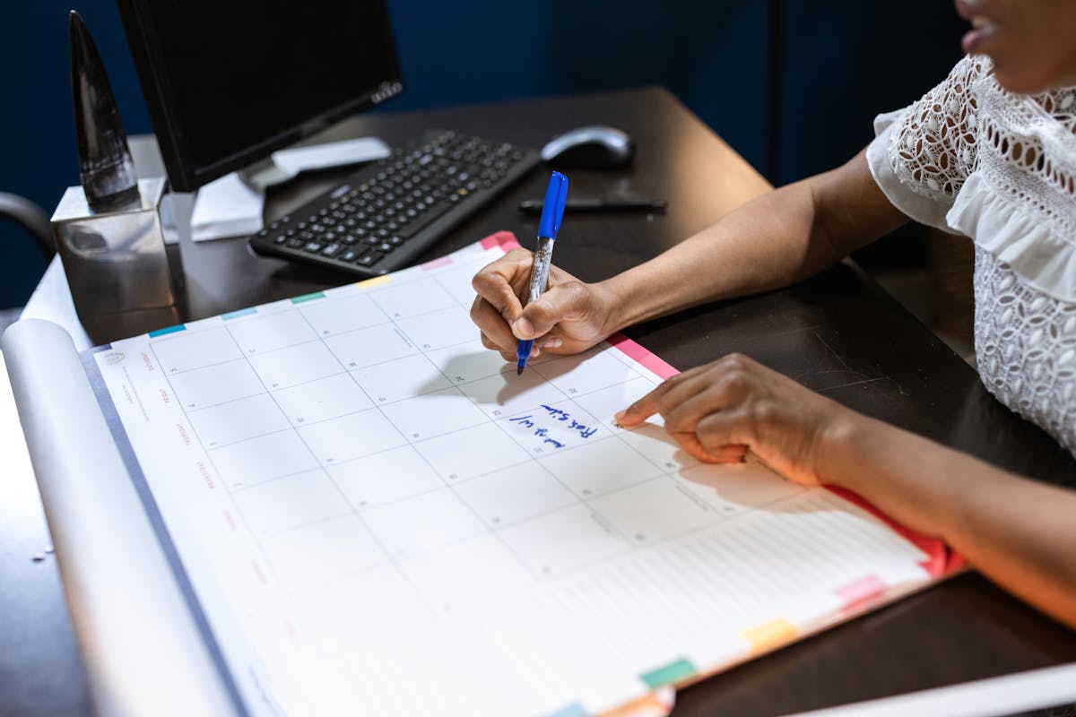 Personne écrivant des notes importantes dans un calendrier de bureau