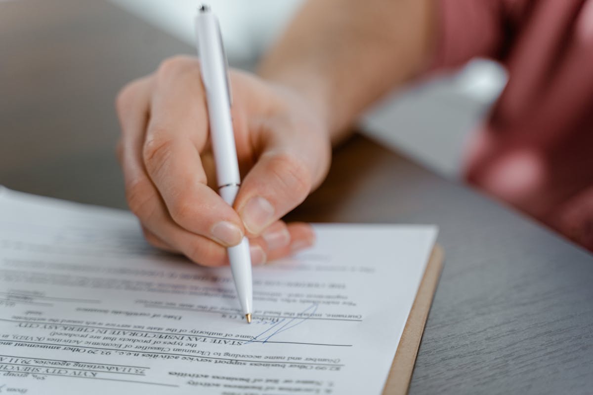 Gros plan d'une main écrivant une signature sur un document officiel