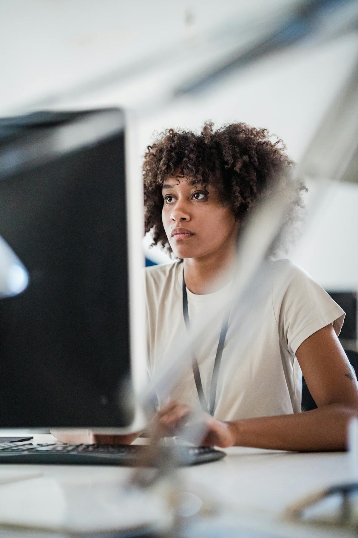 Jeune femme concentrée sur un écran d'ordinateur dans un bureau moderne