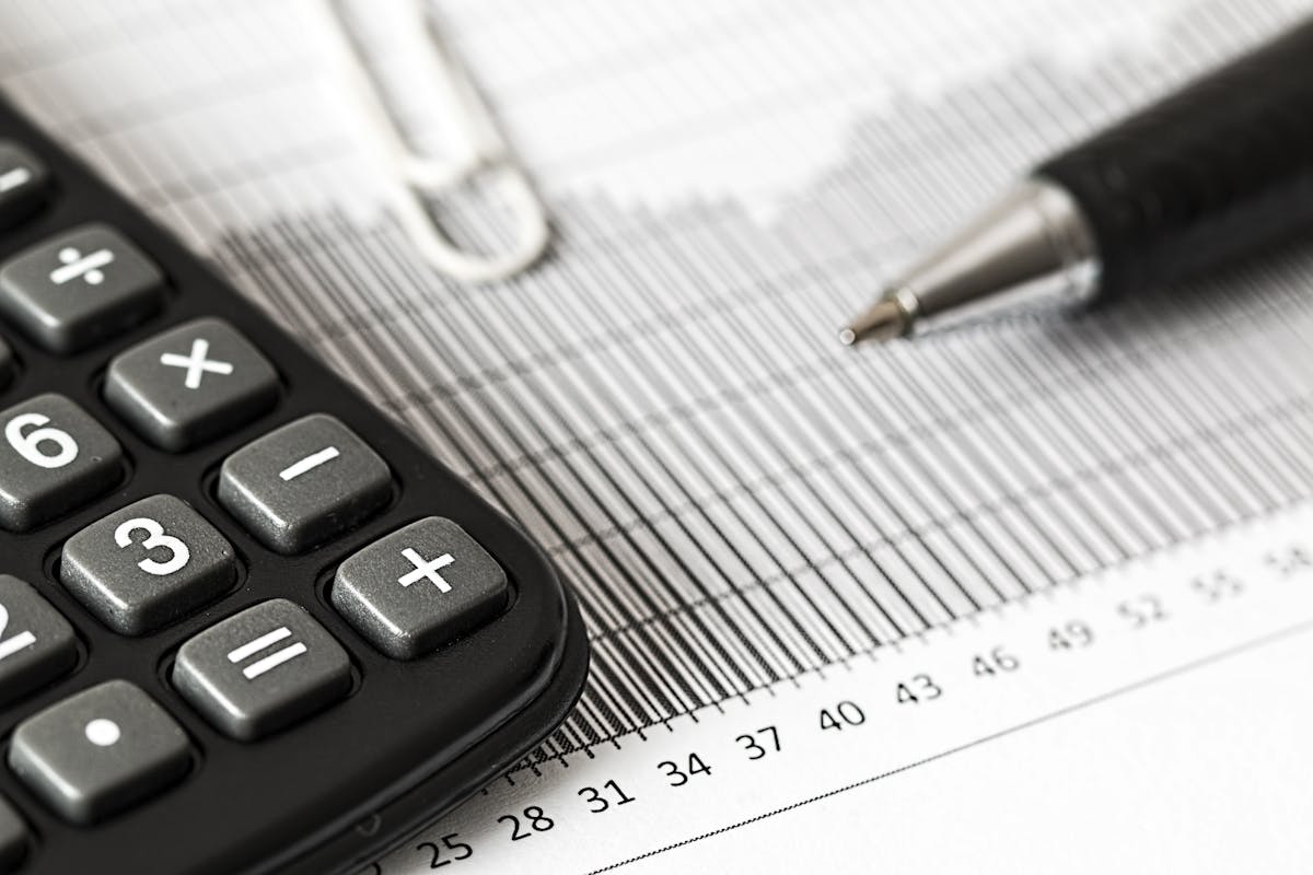 Calculatrice et stylo posés sur un graphique financier