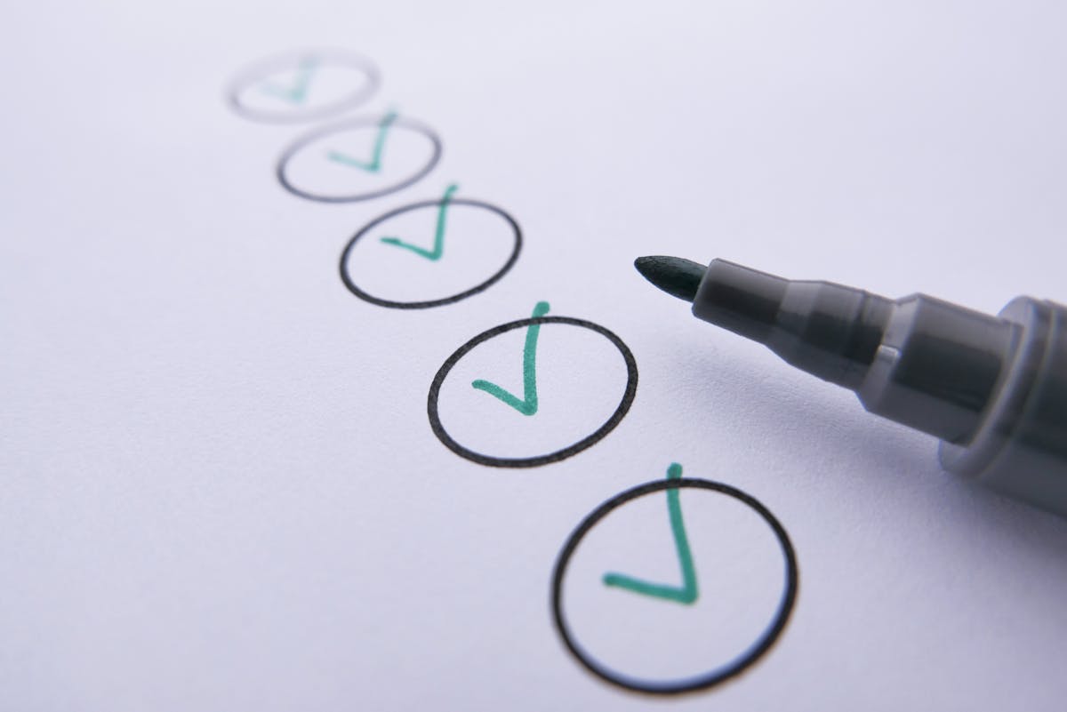 Checklist avec des coches vertes sur du papier blanc, marquées au feutre